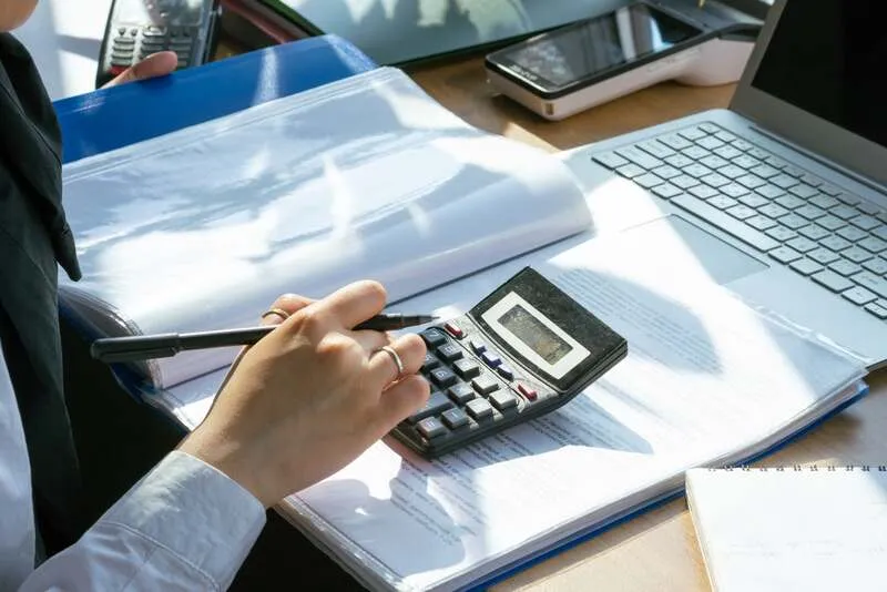 Consultant et gestionnaire vérifient des bulletins de paie et un contrat d'externalisation sur un bureau.